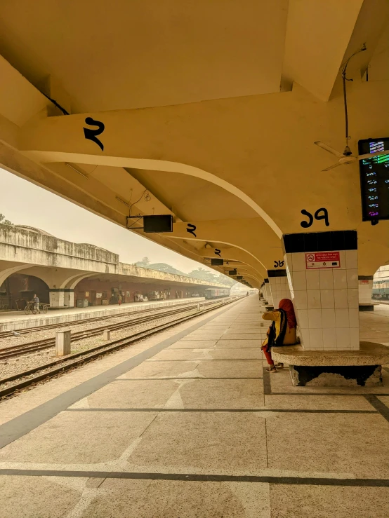 a train platform with a man sitting on a bench