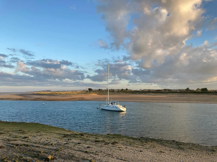 a sailboat on the water with clouds in the background