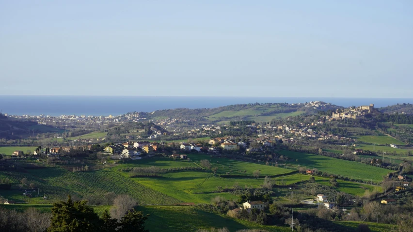 a grassy hill with a view of some city in the distance