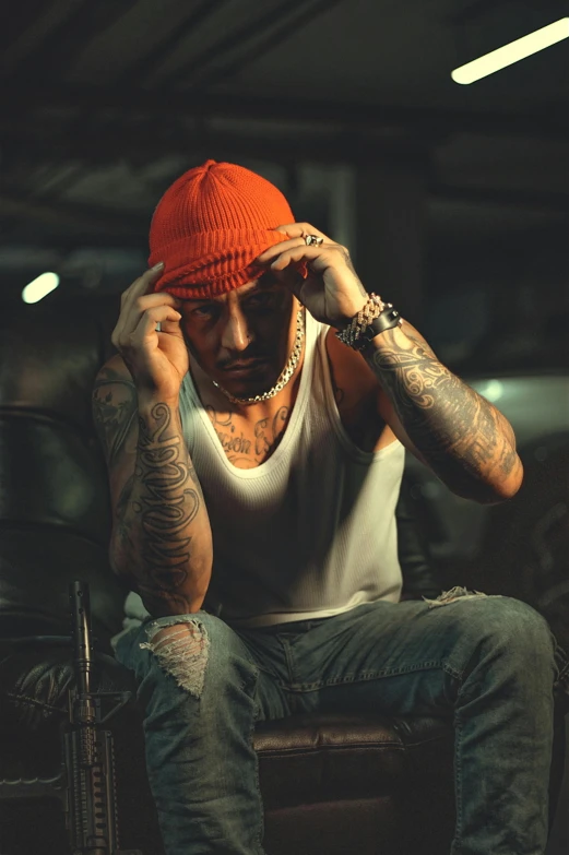 a tattooed man wearing a orange beanie in a room