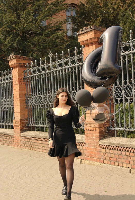 a woman walking in front of a fenced off gate