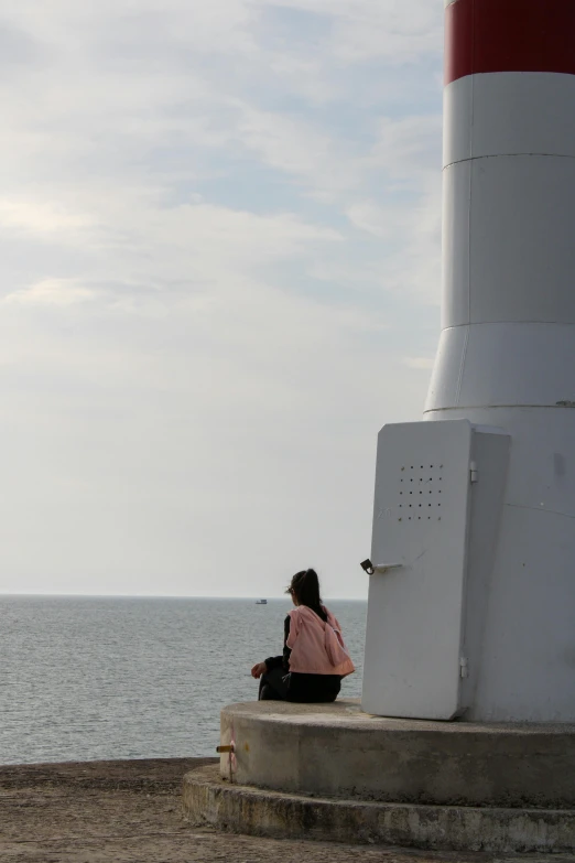 the girl sits at the end of stairs next to a lighthouse