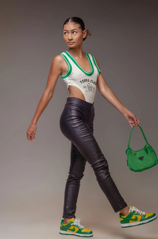 a beautiful young woman in cropped pants holding a green purse