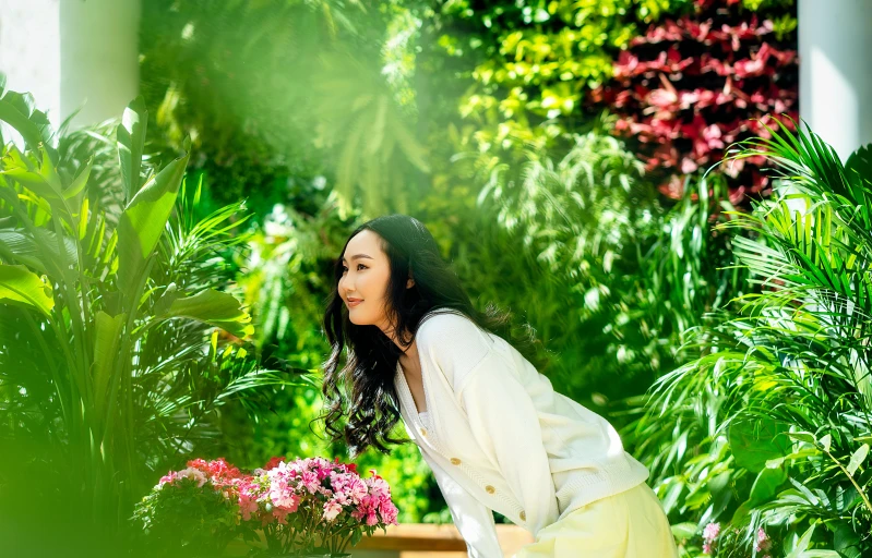 a woman kneeling down by flowers and greenery