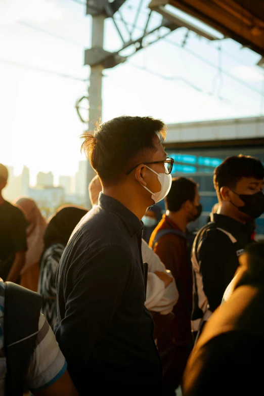 group of people standing at outdoor event with masks covering their faces