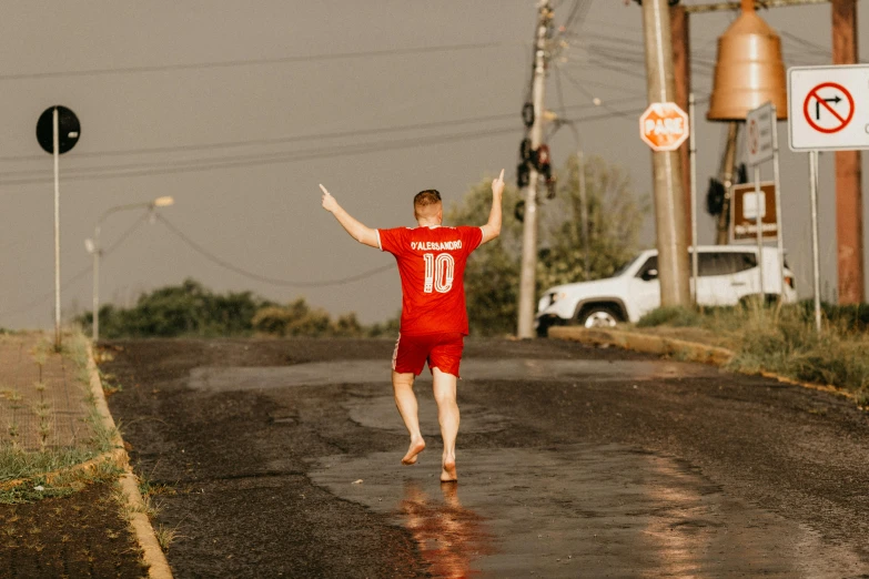 a man in a red shirt is running down the road