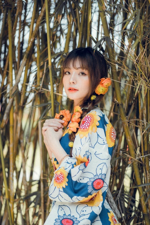 woman in blue and yellow oriental outfit standing in front of bamboo trees