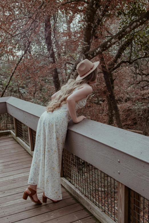 a girl leaning against a fence next to some trees