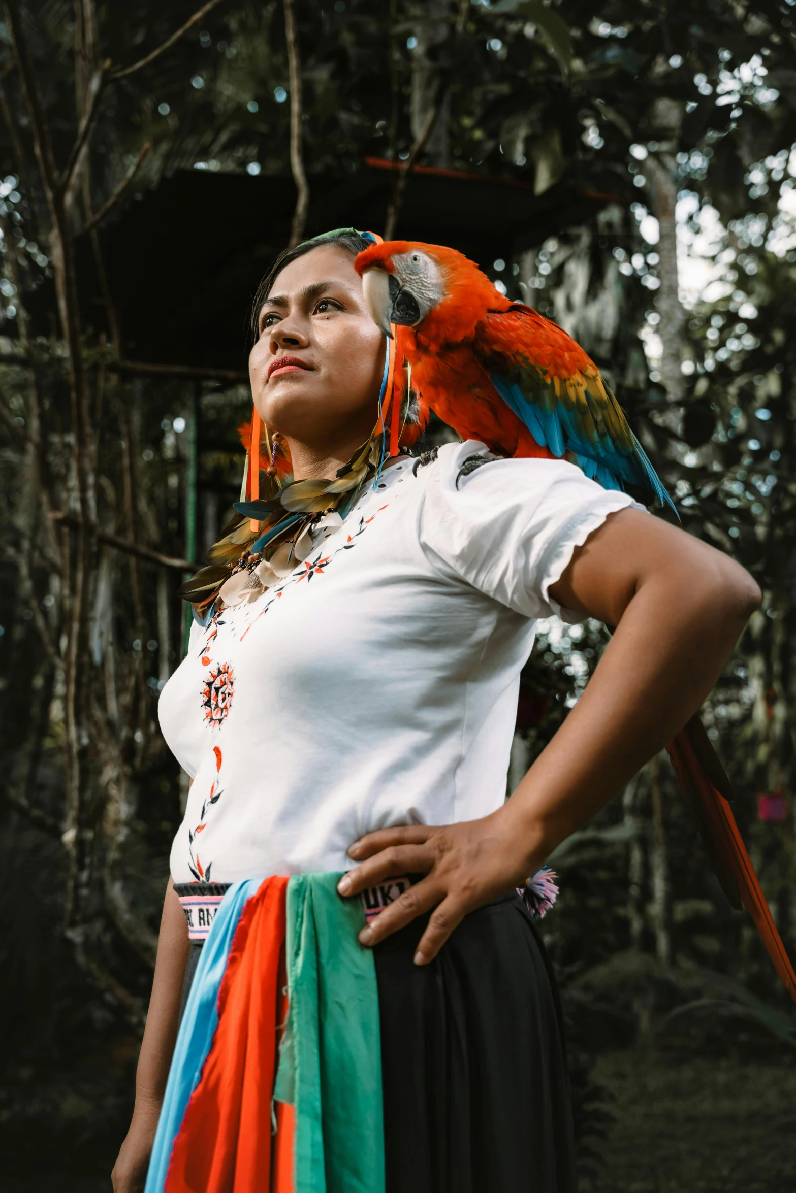 a woman in colorful clothing holding a parrot on her shoulders