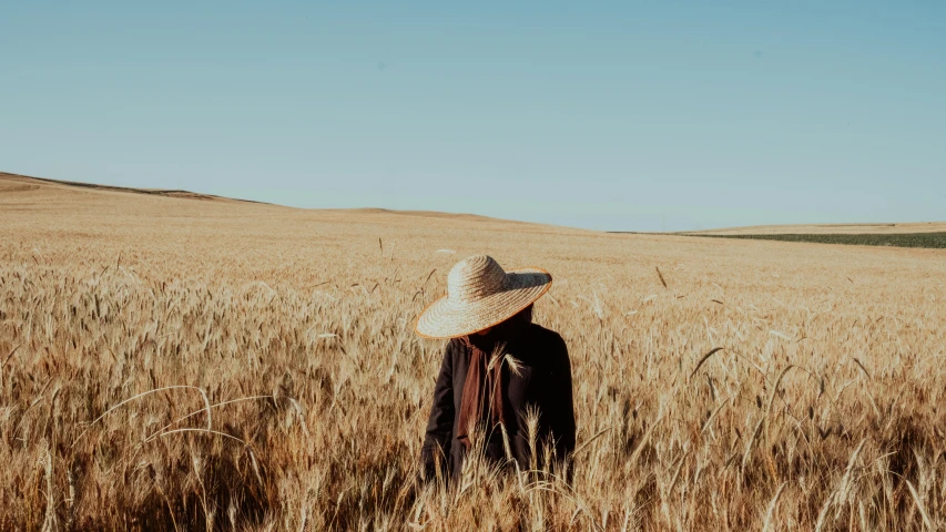 a woman in an open field with a hat on her head