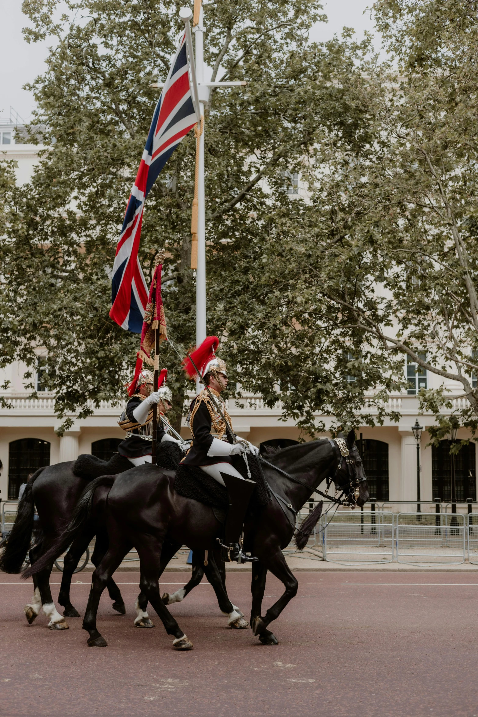 people in uniforms on horses ride through a city square