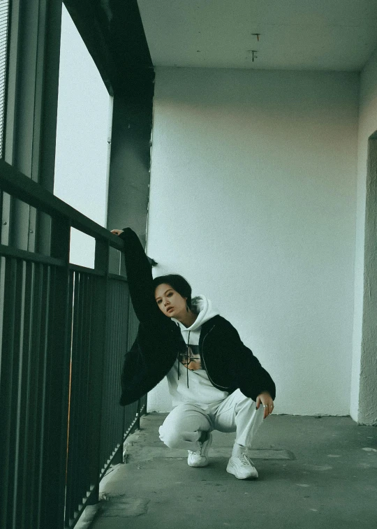 the man poses on the street leaning against a fence