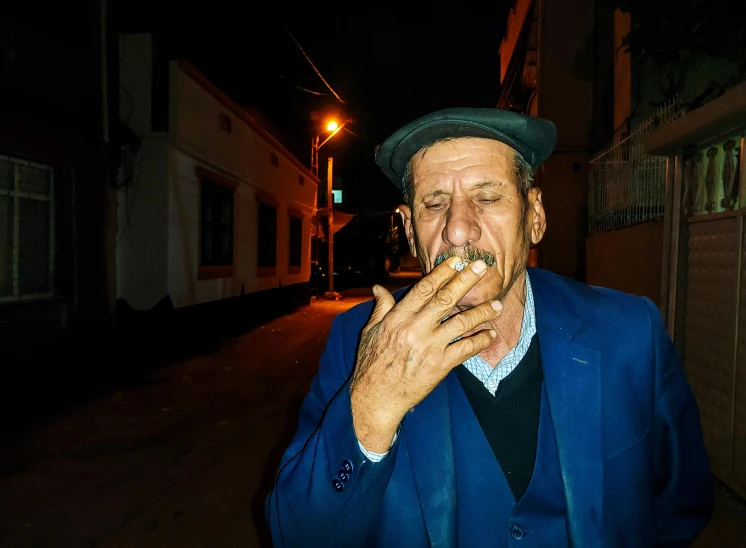 an elderly gentleman in blue jacket eating a piece of food