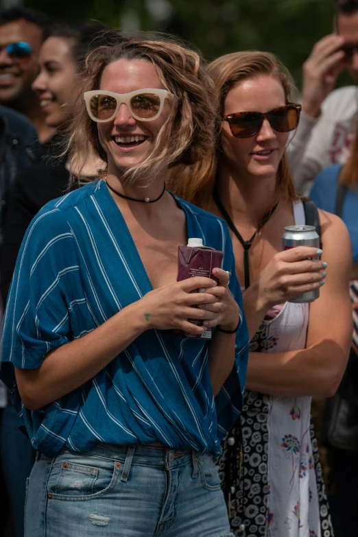 a couple of women with shades on holding cans of beer