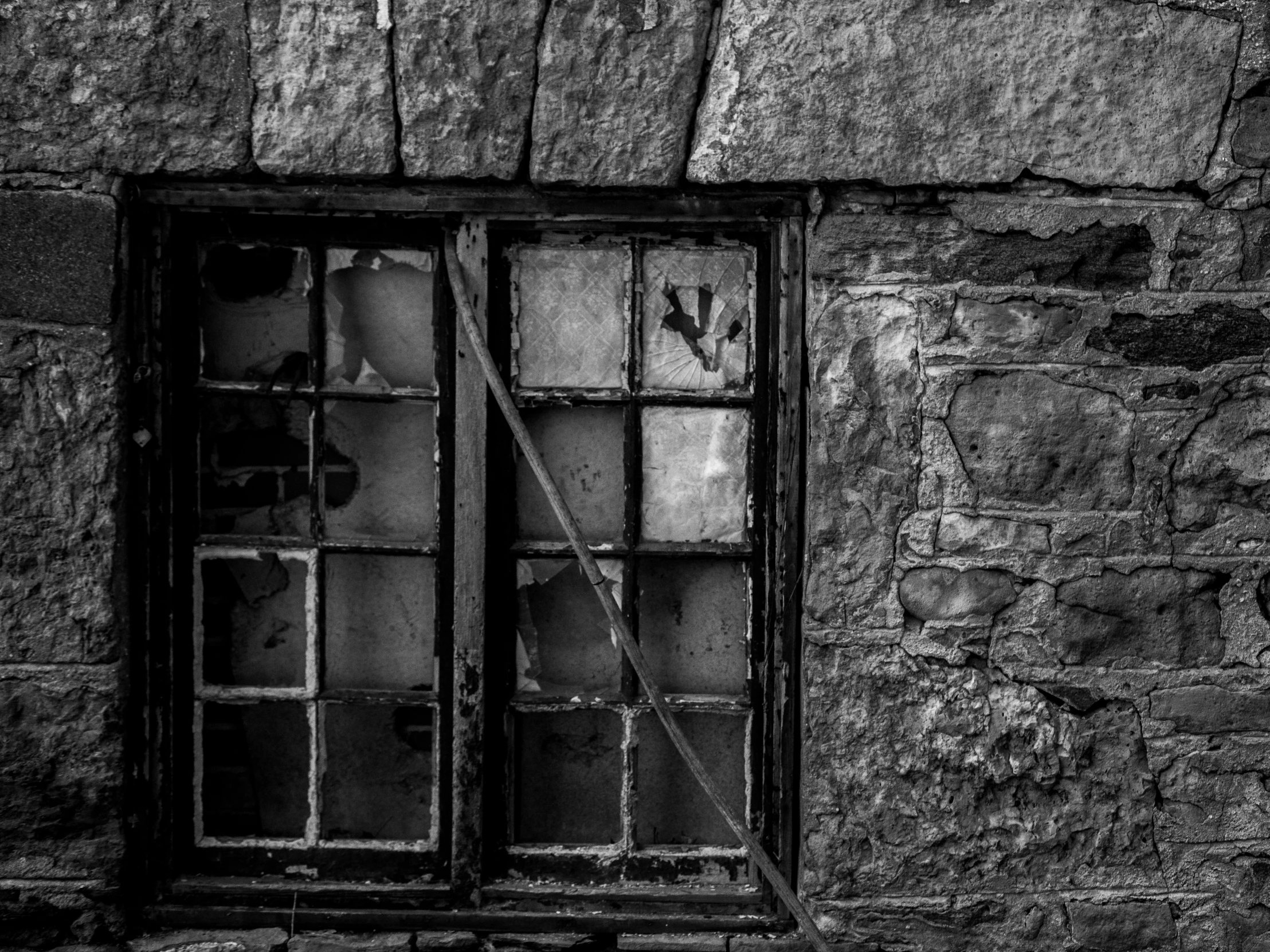 two old windows sitting side by side in a stone wall