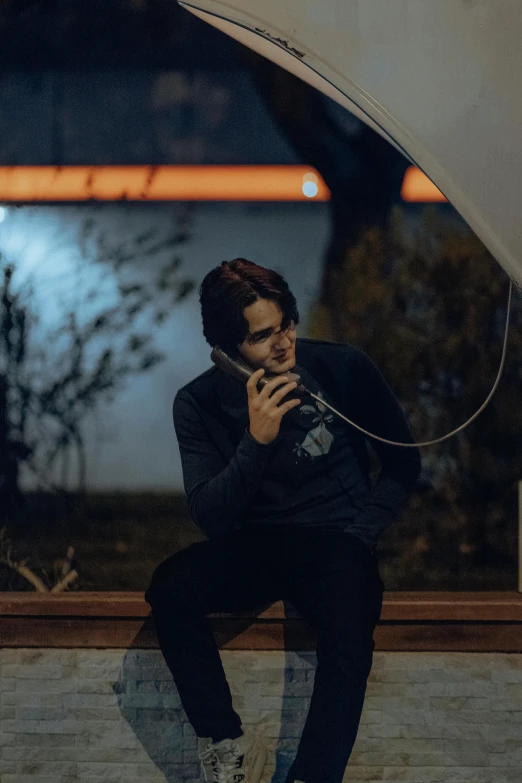 a boy sits on the wall with an umbrella