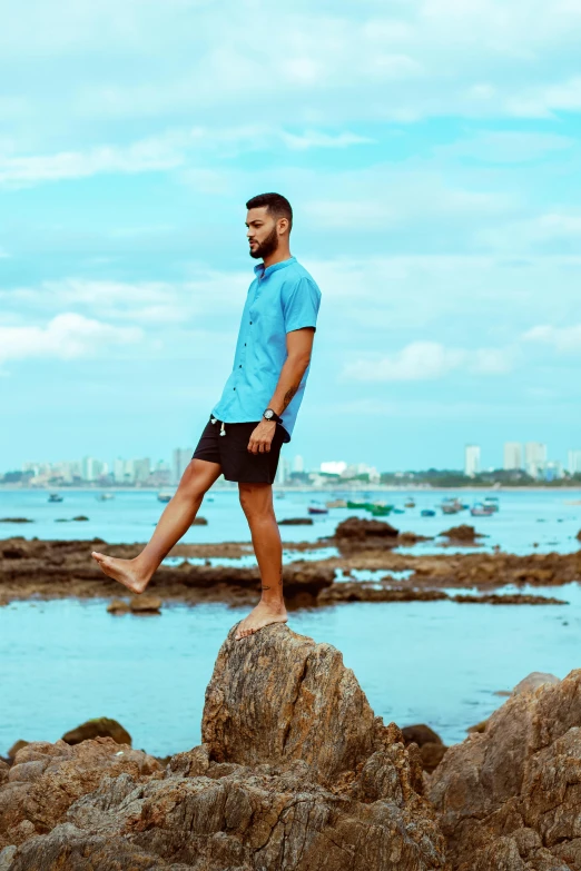 a man is standing on a rock next to the ocean