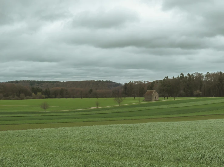 a field with a small building on the other side