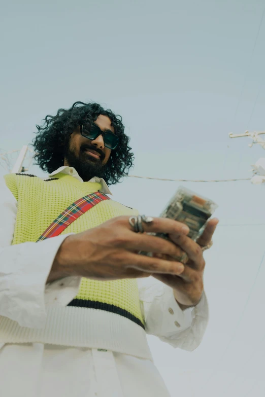 man with long hair in sunglasses looking at cell phone