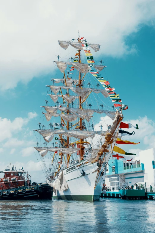 an old boat with many flags attached to it is docked at the dock