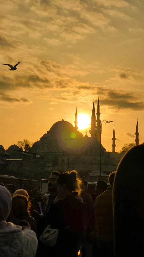 a group of people standing around watching the sun set