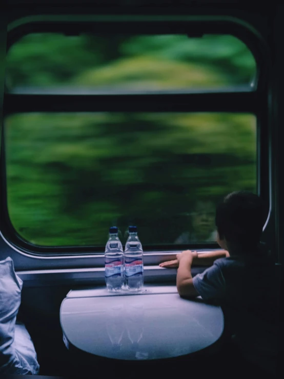 a young person sitting at a table on the train