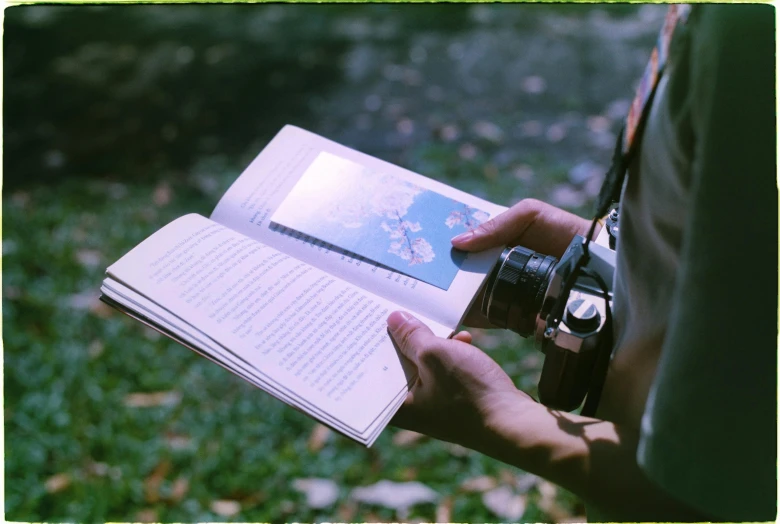 a man holding a book while looking through a camera