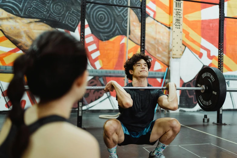 a man and woman doing squats in front of a wall of paintings