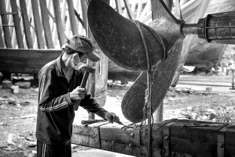 man in hat and overalls using electric grind