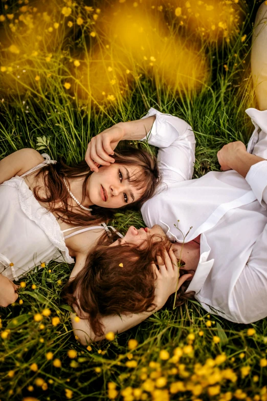 two people laying in the grass on each other