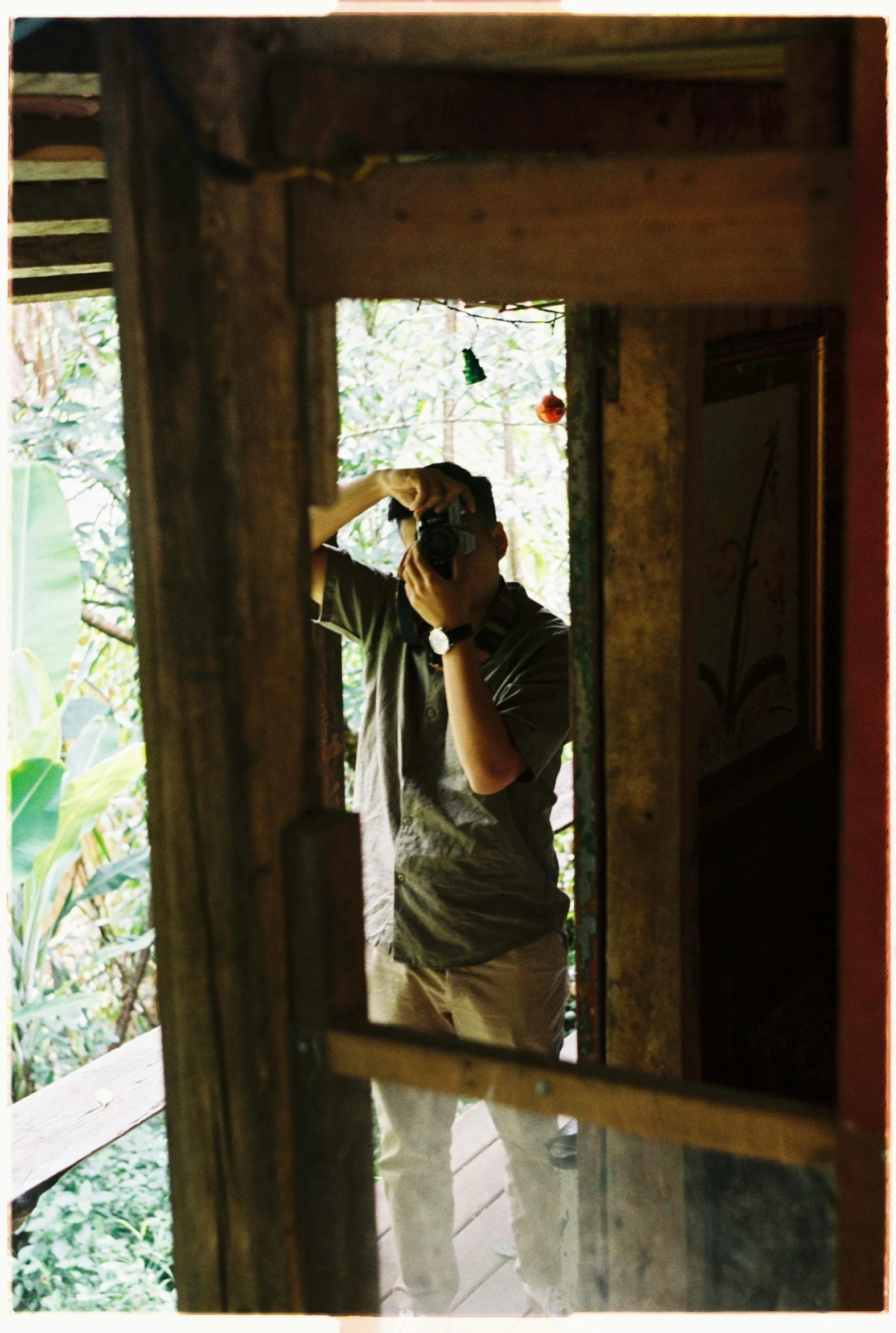 a man taking a po from behind a window in the outdoors