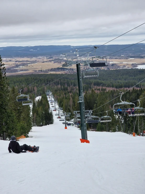 a man lies down in the snow while on his board