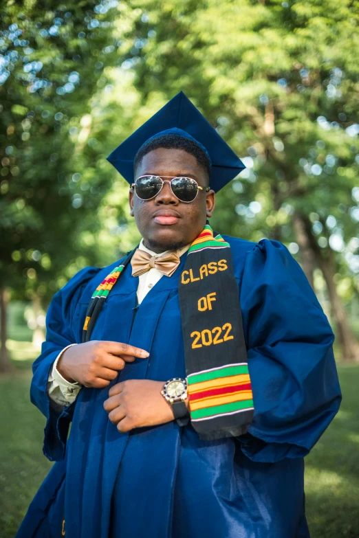 man dressed in graduation gown and shades wearing a hat and gown