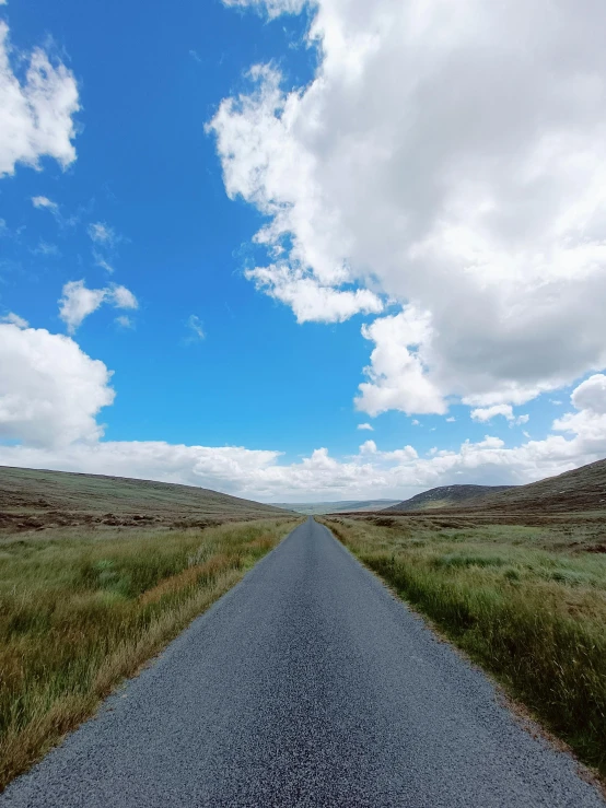 a long open field with an empty road