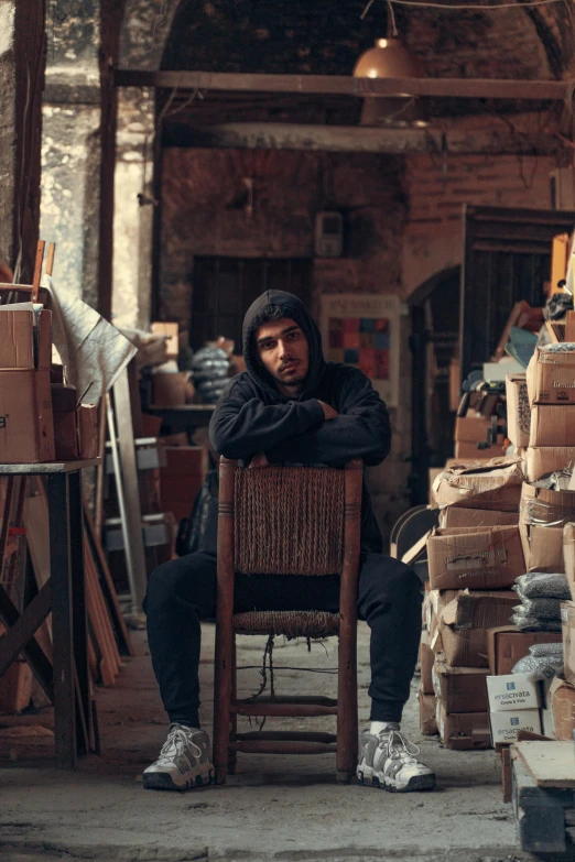 a man sitting on a chair near piles of boxes and crates