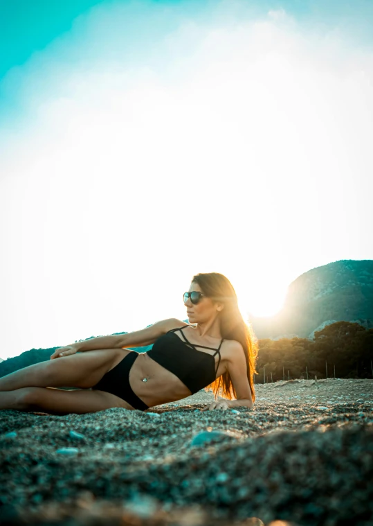 the girl is laying down on the beach looking at soing