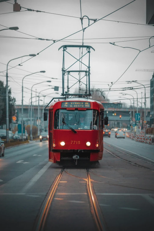 a red train coming down the track in front of a bunch of cars