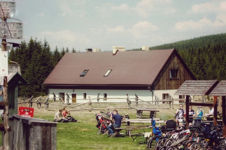 people in a field outside an old fashioned farm house