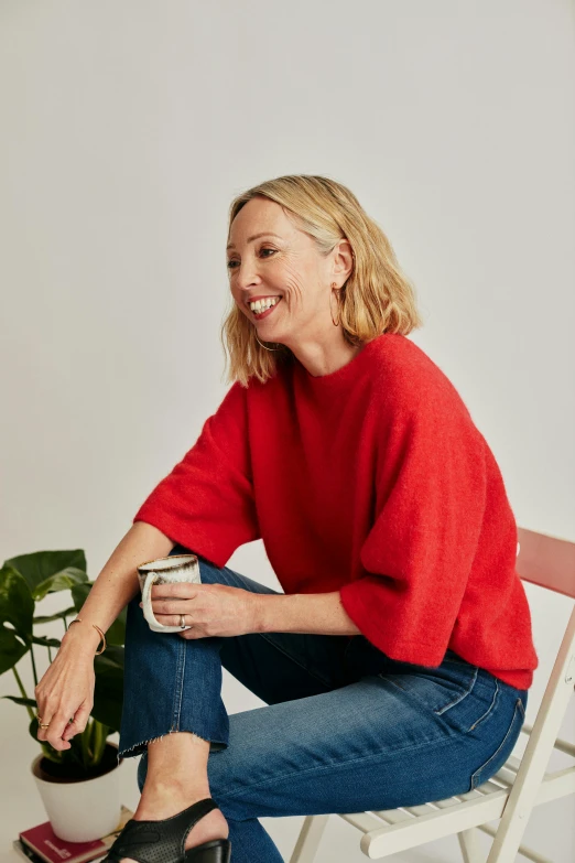 a woman sitting in a chair holding a coffee cup