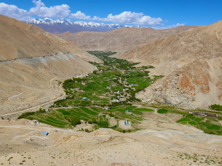 green valley surrounded by mountains under a blue sky