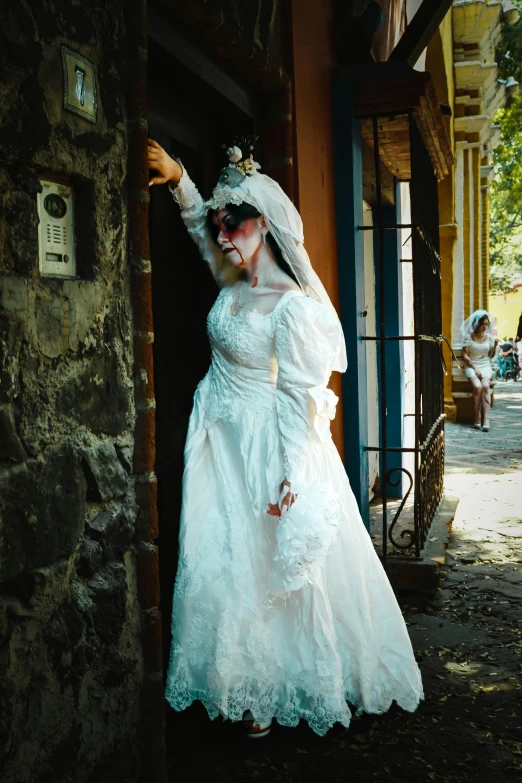 a woman wearing a white dress stands on the side of a building