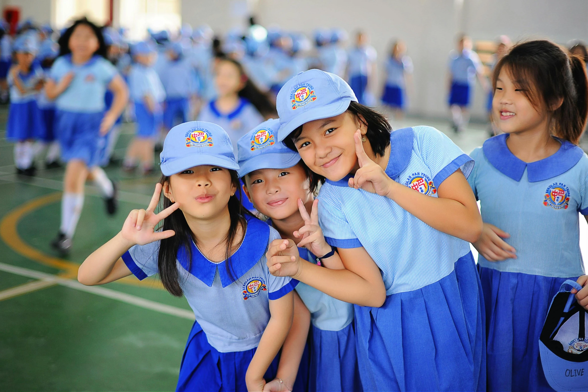 three s smiling and making peace signs in a gymnasium