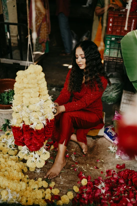 a woman in a red outfit is kneeling by a bunch of flowers