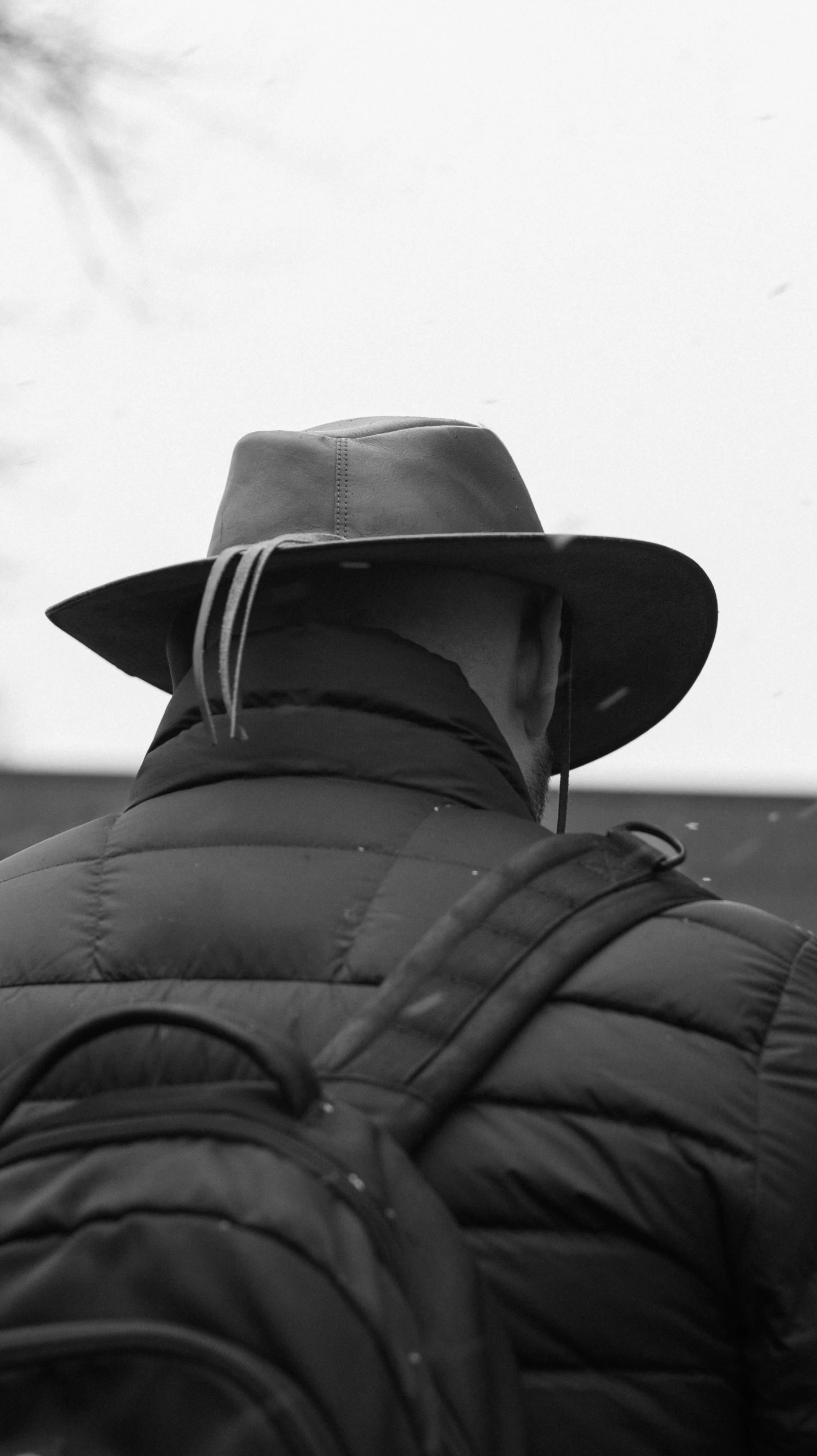 a man in a hat and a coat standing outside