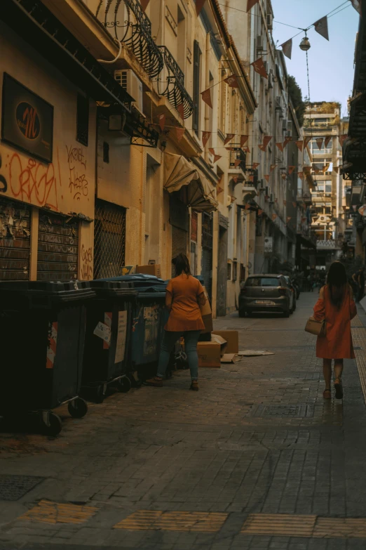 people are walking down a street beside a building