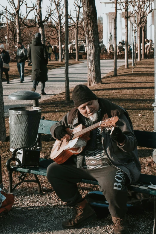 man playing the guitar on the park bench