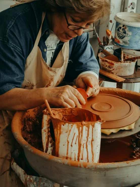 a person in an apron is  cake into slices