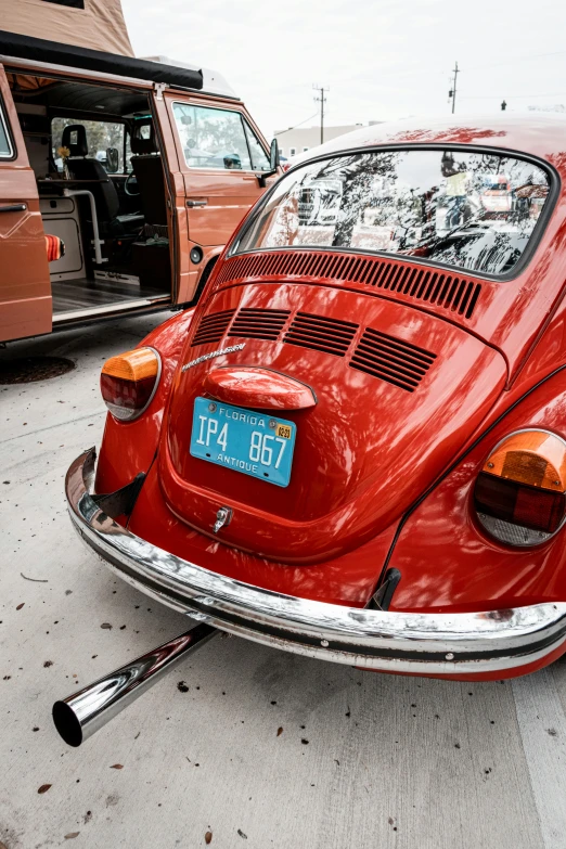 a red beetle parked on the street next to another car