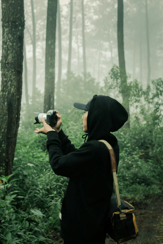 a woman takes pictures in the woods with a camera