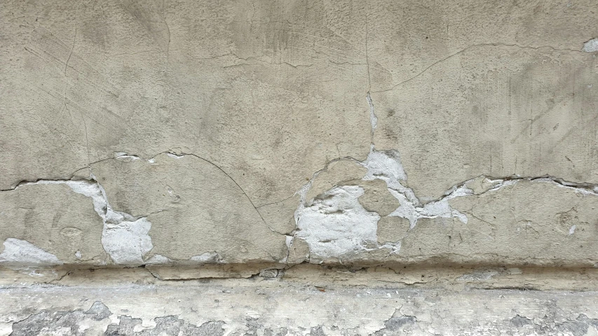 a grey cement wall has chipped paint on it